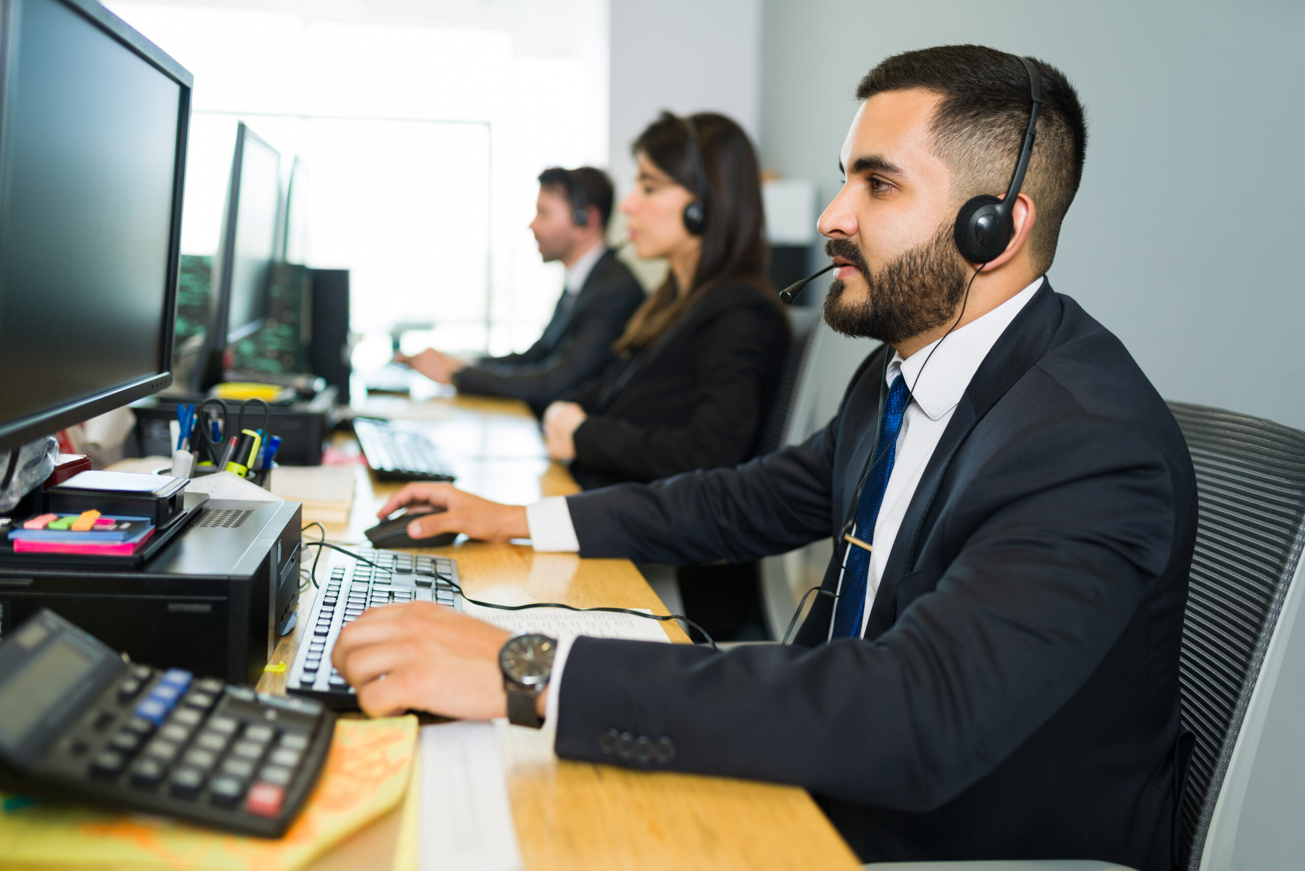 Attractive latin executive offering customer service with a headset and offering tech support at a busy call center